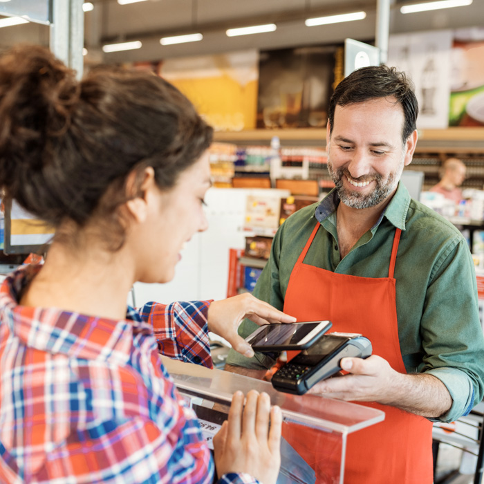 Woman uses contactless payment to checkout with cashier